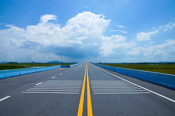 istock Empty road and the yellow traffic lines with clouds. 476935314