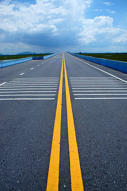 istock Empty road and the yellow traffic lines with clouds. 476935324