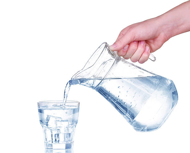 istock Pouring water from glass pitcher on white background 476936206