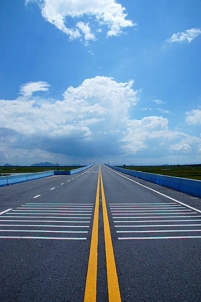 istock Empty road and the yellow traffic lines with clouds. 476938784