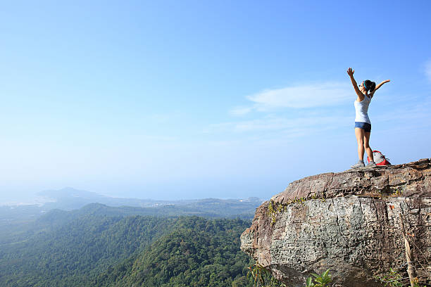 istock cheering young woman hiker open arms at mountain peak 476943264