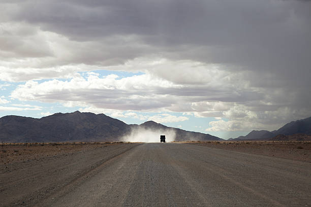 A jeep travels a sandy track in Etosha National Park at sunset.