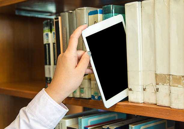 Closeup hand putting a tablet pc in the shelves in the library