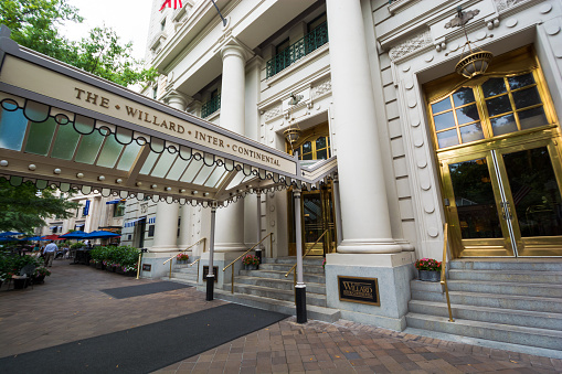 Washington, United States - August 19, 2014: People meander about the sidewalk outside The Willard InterContinental Washington, a Beaux-Arts hotel located at 1401 Pennsylvania NW, during the daytime while other people meander about further down the sidewalk. It is situated two blocks east of the White House.