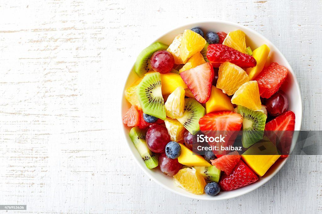 Fresh fruit salad Bowl of healthy fresh fruit salad on wooden background. Top view. Fruit Stock Photo