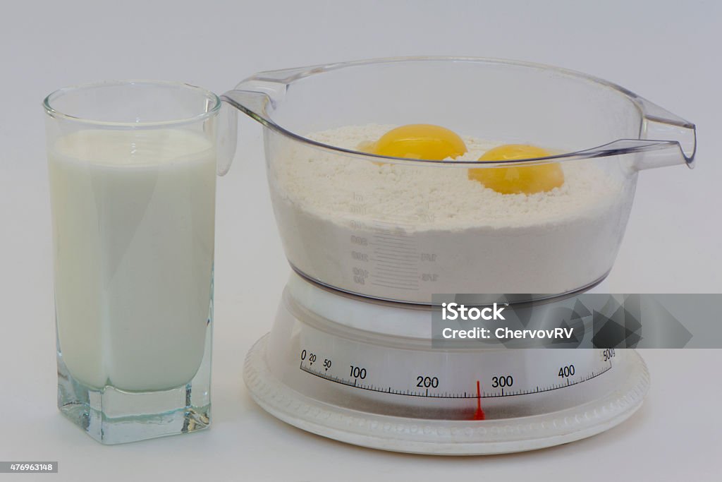 scales with flour and a yolk and milk scales with flour and a yolk in a measured cup with a glass of milk 2015 Stock Photo