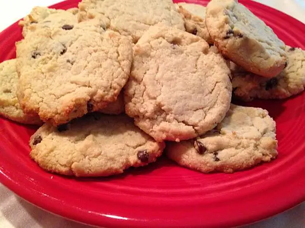 Fresh baked chocolate chip cookies on a bright red plate.