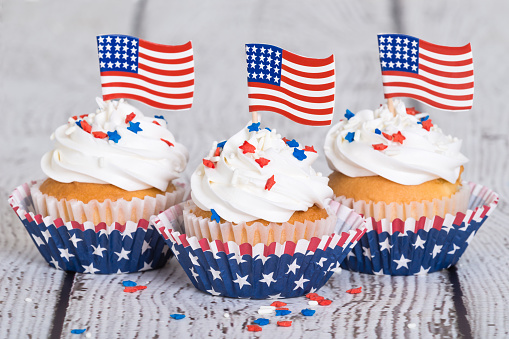 Patriotic cupcakes with sprinkles and American flags on vintage background