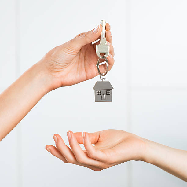 Woman receiving house key Closeup shot of a female hand receiving house key. Woman buying new home. Close up hand holding house key. passing giving stock pictures, royalty-free photos & images