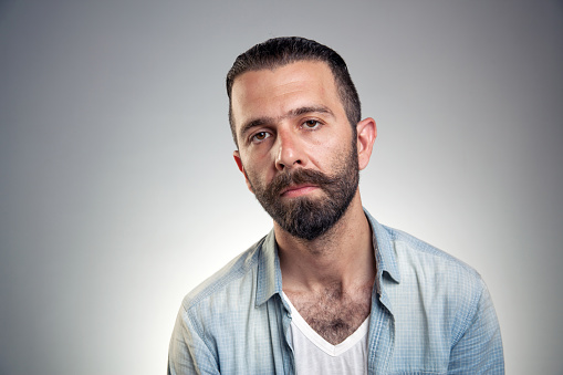 Portrait of a bearded young man against gray background