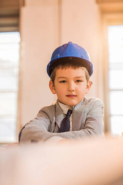 istock Little boy engineer wearing blue hardhat and looking at camera. 476988610
