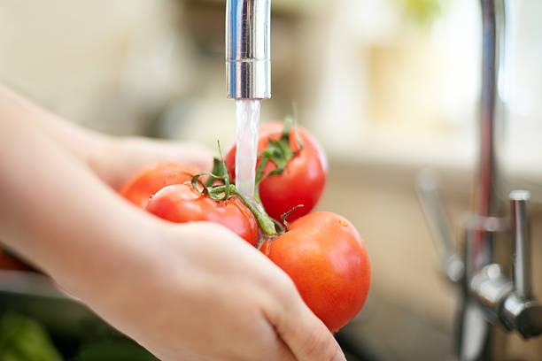 istock Close-up of hands washing tomatoes under running water 476988896