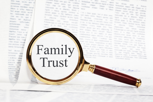 Family Trust Concept - paperwork representing a Family Trust, with a magnifying glass over, highlighting Family Trust.