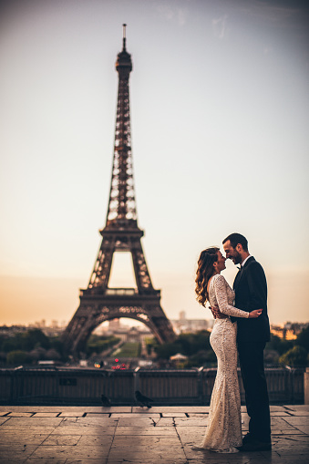 Photo of young married couple kissing in front of an Eiffel tower.