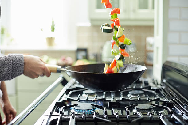 istock Man tossing fresh vegetables in saucepan 477000030