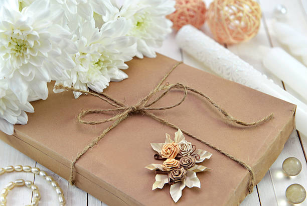 Close up of gift in brown wrapped paper with beautiful white flowers and trinkets