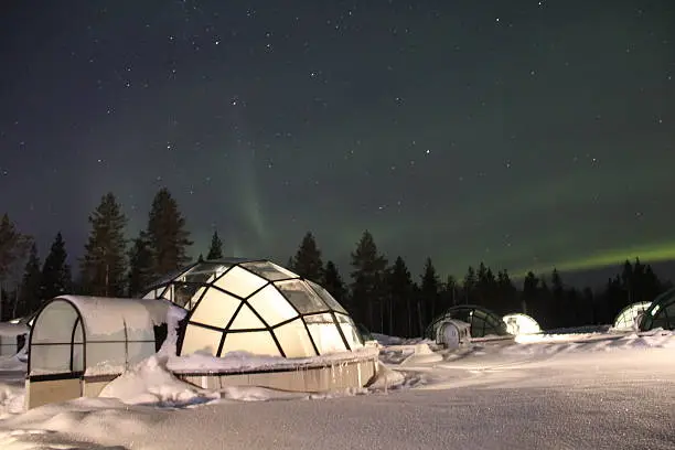 Northern Lights (Aurora Borealis) dancing above Glass Igloos in Lapland, Finland.