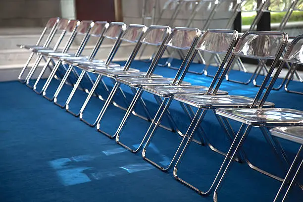 Row of metal folding-chairs on blue carpet