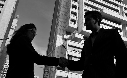 Silhouette of Men and Women Shaking Hands Near Business Buildings.