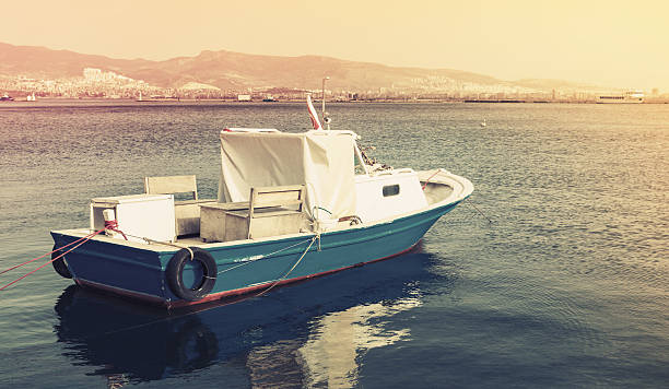 Old wooden pleasure boat anchored in Izmir bay, Turkey. Vintage stylized photo with yellow tonal correction photo filter, old style