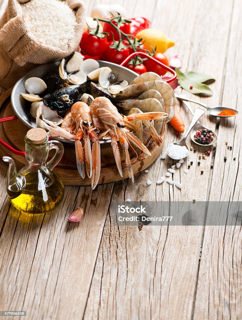 Seafood for typical spanish paella Uncooked seafood and vegetables ready to be prepared for spanish paella on a old wooden background Ingredient Stock Photo
