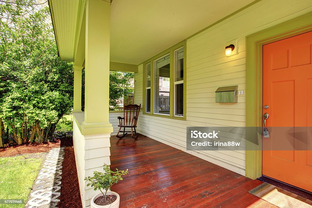 Bright colors porch Open green porch with orange entrance door and rocking chair Architecture Stock Photo
