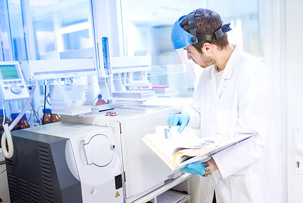 Scientist using manual for programming a chemical computer machinery Scientist using manual for programming a chemical computer machinery in laboratory radioactive stock pictures, royalty-free photos & images
