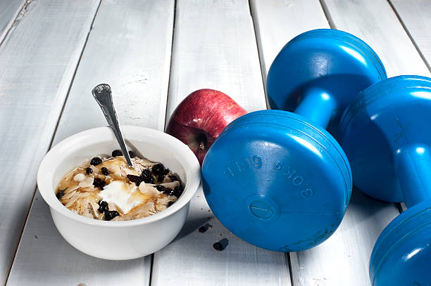 Dumbbells and red apple next to bowl with yogurt stock photo