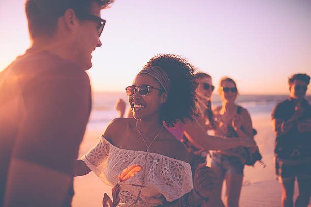 afro chica bailando con su novio en un atardecer beachparty - beach party friendship teenage girls fotografías e imágenes de stock