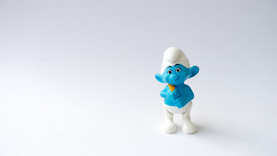 Kuala Lumpur, Malaysia - April 18, 2015: Cute Smurf toy figure on plain background. The Smurfs is a Belgian comic and tv franchise centered on a fictional colony of small blue creatures in the forest