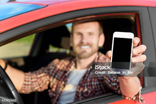 Man In Car Driving Showing Smart Phone Stock Photo - Download Image Now - 2015, Car, Holding