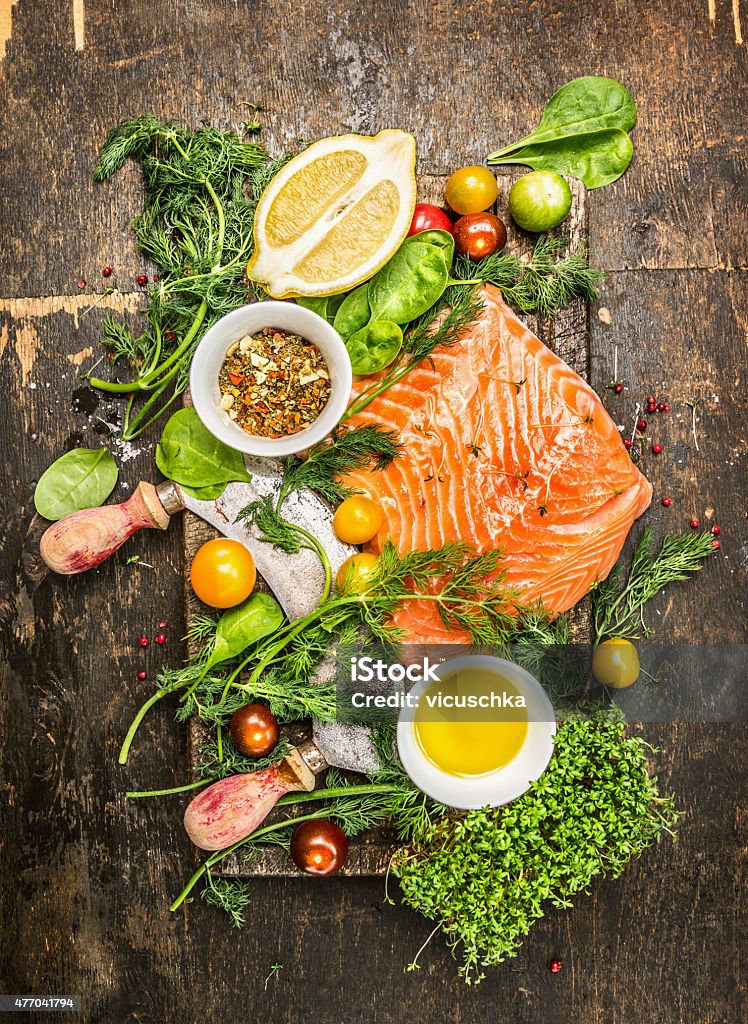 Salmon fillet with fresh healthy herbs,vegetables, oil and spices fresh salmon fillet with fresh healthy herbs,vegetables, oil and spices on rustic wooden background, top view Vegetable Stock Photo