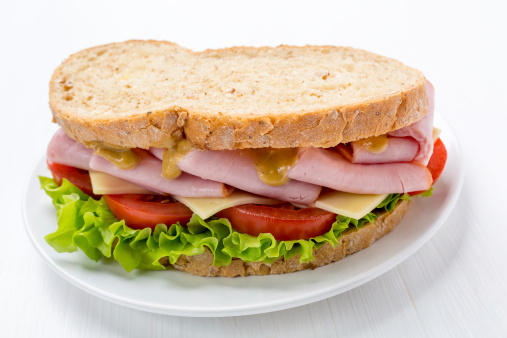 Big and Healthy Ham, Lettuce, Cheese and Tomatoes Sandwich on Whole Grain Bread with Mustard