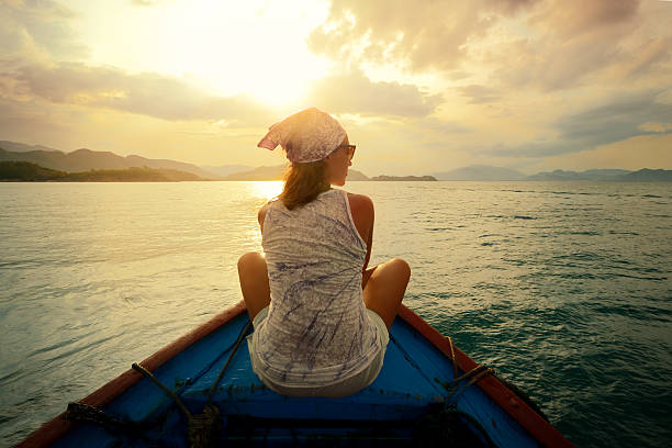istock Woman floating in boat at sunset 477061785