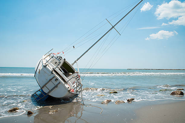 barca a vela e distrutte piedi sulla spiaggia - storm sailing ship sea shipwreck foto e immagini stock