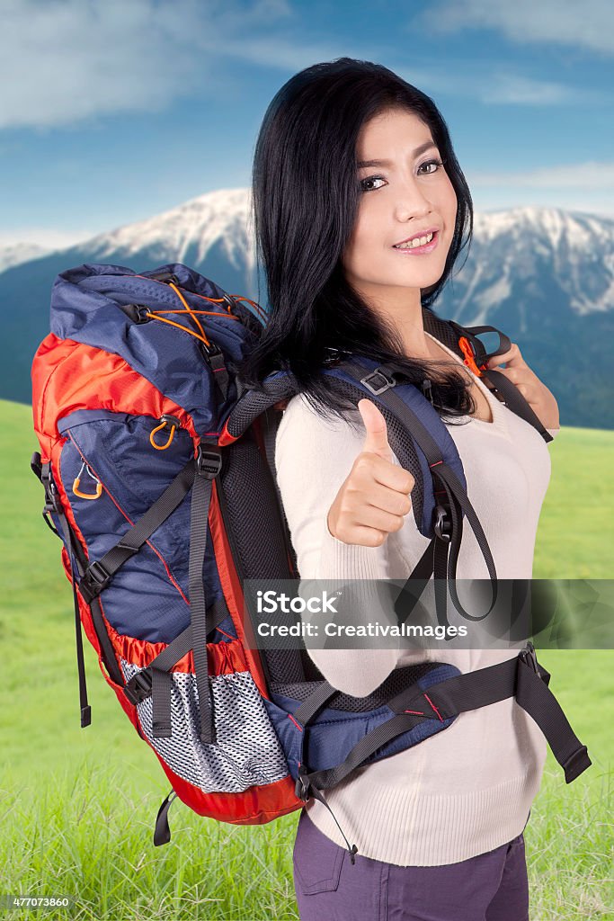 Young hiker showing thumb up Beautiful woman carrying rucksack for hiking on the mountain, showing thumb up on the camera 2015 Stock Photo