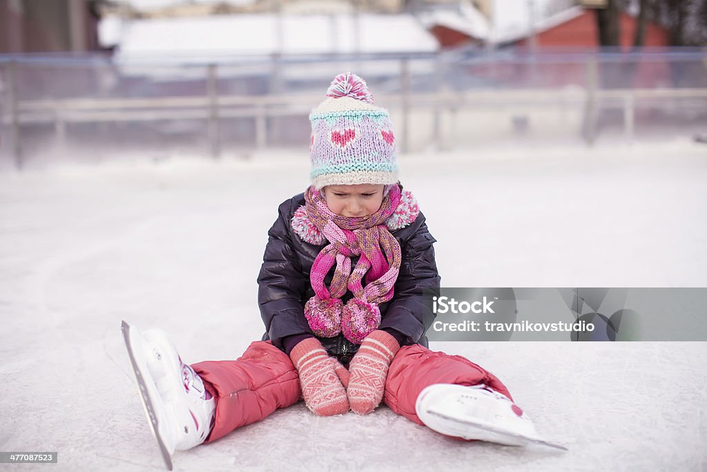 Triste ragazza piccola seduta su una pista di pattinaggio dopo l'autunno - Foto stock royalty-free di Ambientazione esterna