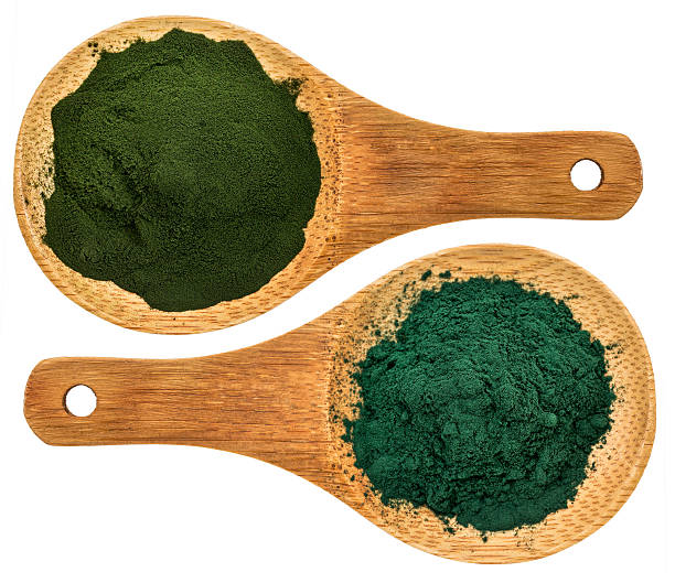 chlorella ans spirulina supplemt powder chlorella ans spirulina supplemt powder - top view of isolated wooden spoons chlorella stock pictures, royalty-free photos & images