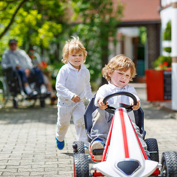 dos hermanos felices niños jugando con coche de juguete - car child teamwork sports race fotografías e imágenes de stock