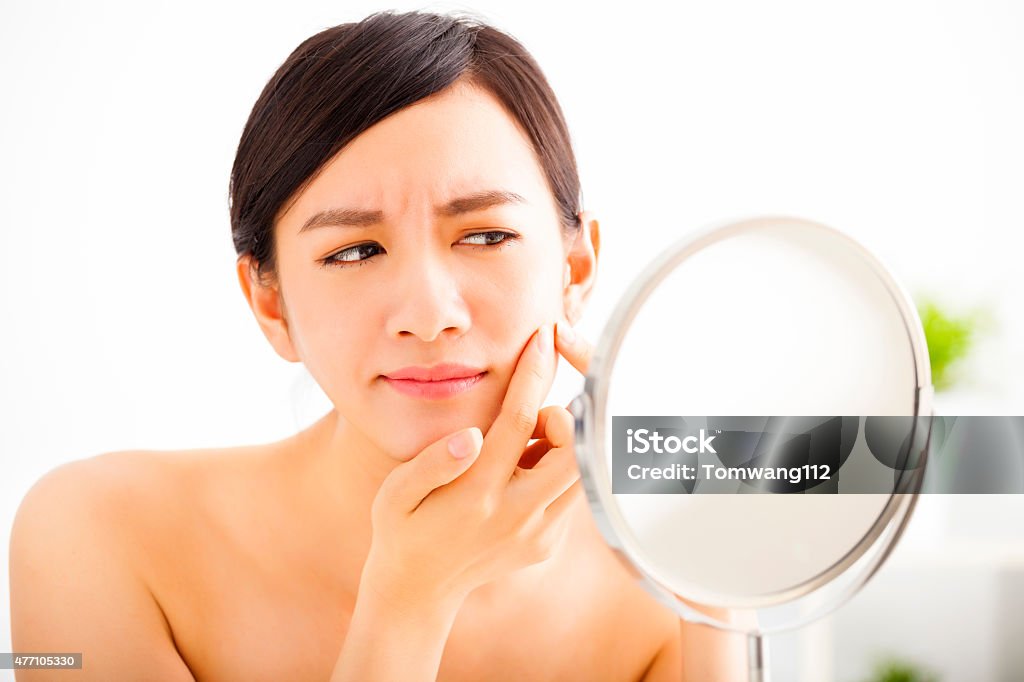 young woman Squeezing pimple looking on mirror Acne Stock Photo