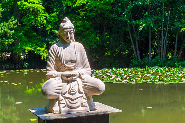 A serene Buddha statue sits peacefully by a koi pond, symbolizing mindfulness, tranquility, and spiritual meditation in nature. Bali, Indonesia.