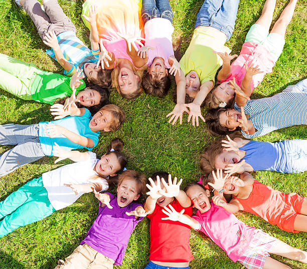 многие дети с поднимая руки на траве - circle group of people human hand student стоковые фото и изображения