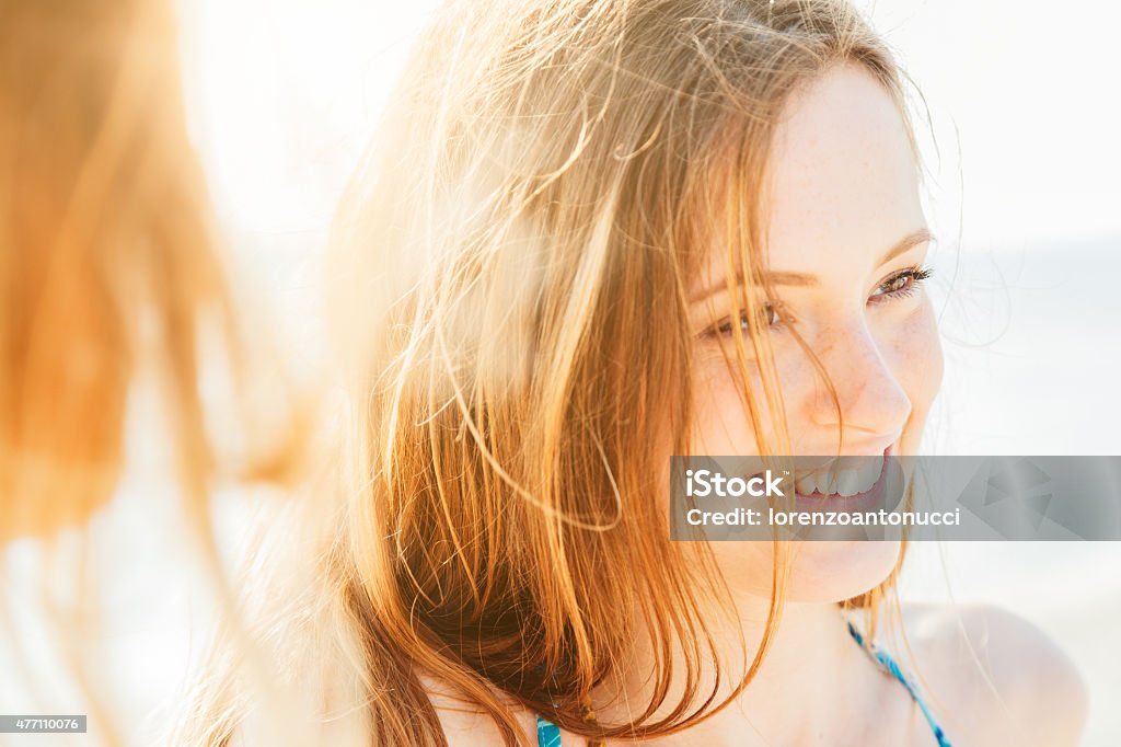 Retrato de una mujer sonriente en la playa al atardecer - Foto de stock de Mujeres libre de derechos