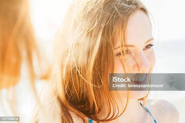 Retrato De Una Mujer Sonriente En La Playa Al Atardecer Foto de stock y más banco de imágenes de Mujeres