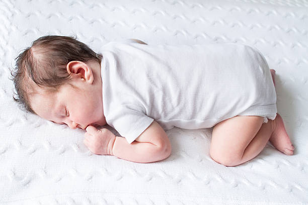 istock Tiny newborn baby sleeping on a white knitted blanket 477113609