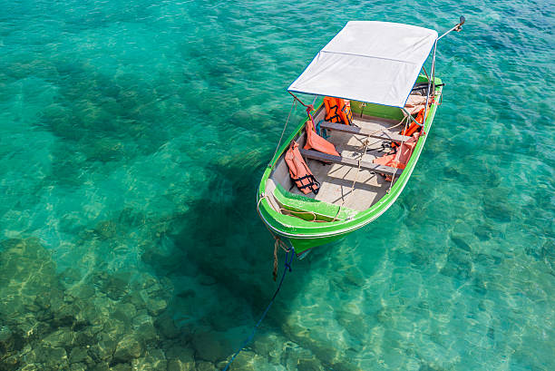 istock Small green boat floating on the clear water 477114054