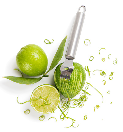 Top view of lime with leaves, lime zest with zester isolated on a white background.