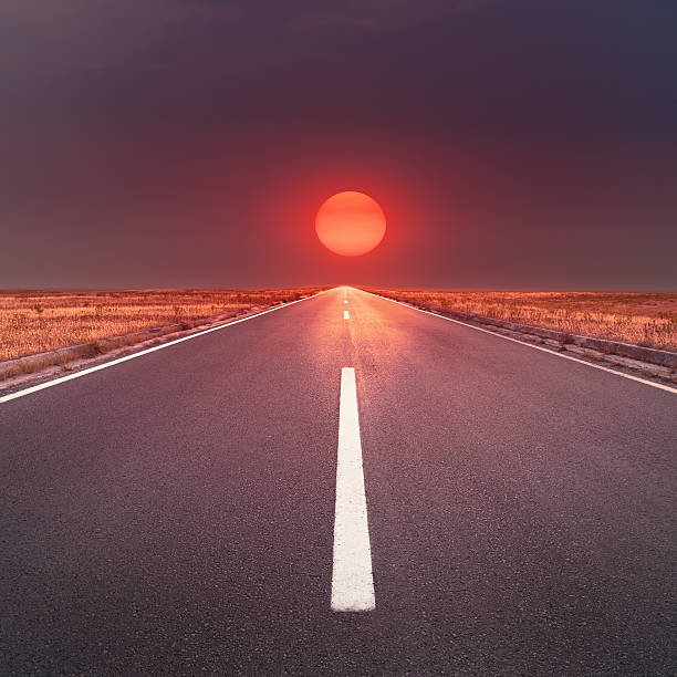 istock Driving on an empty asphalt road towards the setting sun 477115587