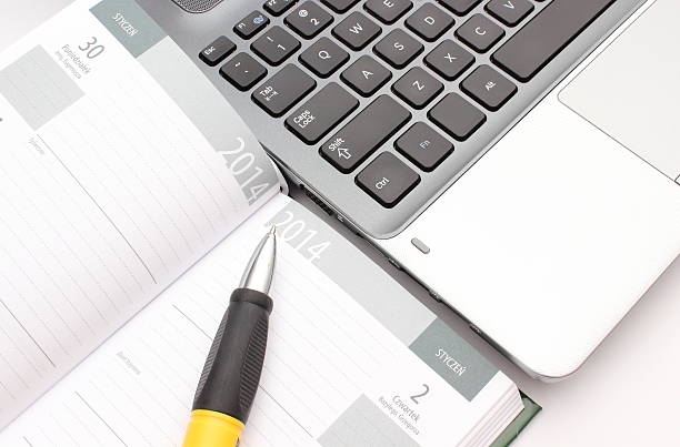 istock Pen on calendar and laptop keyboard 477116787
