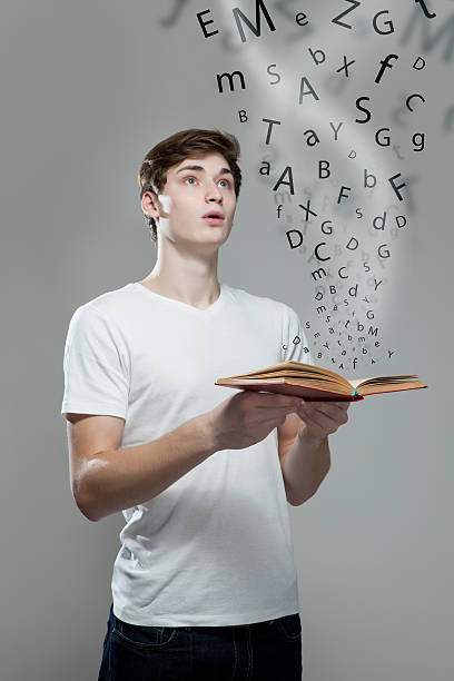 istock Young man holding a book with alphabet letters 477117934